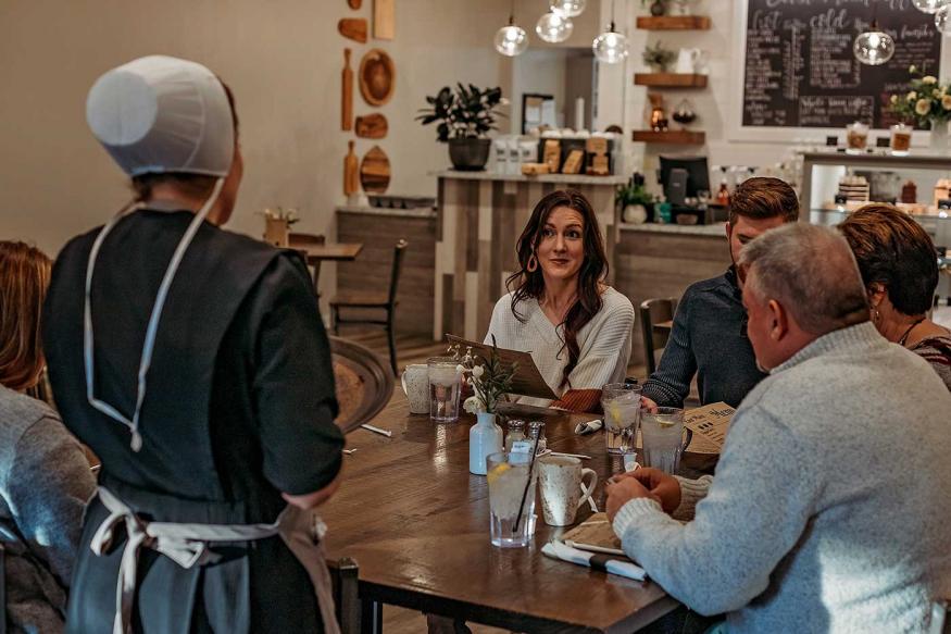 Family at a restaurant being served by an Amish woman